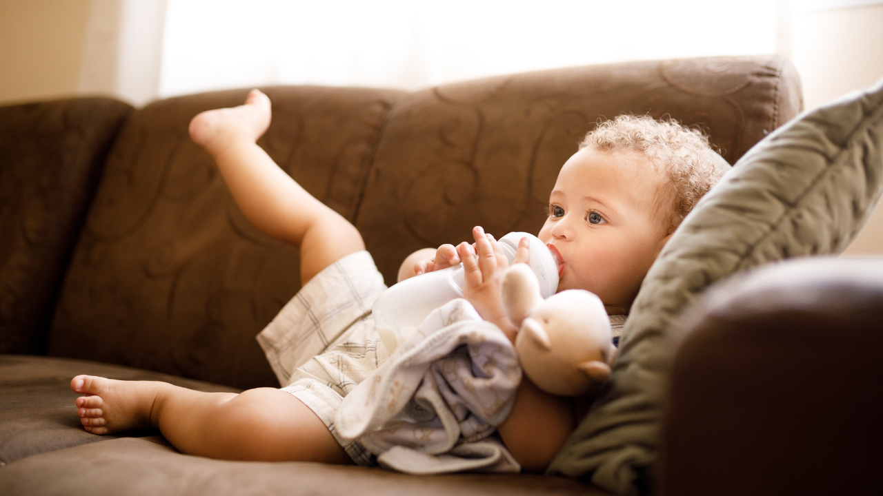 When do babies hold their own bottle?